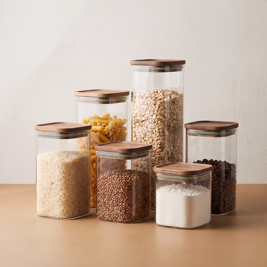 Clear pantry canisters with walnut lids filled with dry goods